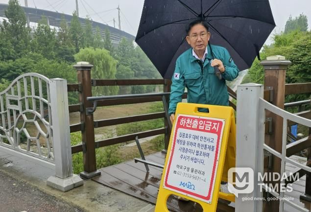 박강수 마포구청장이 집중호우에 대비해 월드컵천에 안내판을 설치하고 있다.