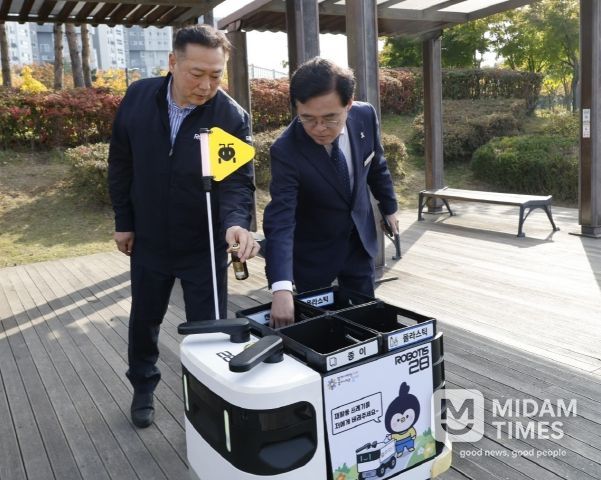 진교훈 서울 강서구청장(오른쪽)이 마곡하늬공원에서 열린 ‘AI 기반 자율주행 로봇서비스 실증 시연회’에서 빈 캔을 수거함에 넣고 있다.
