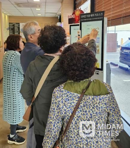 밀양시 삼문동 맥도날드 밀양DT점에서 열린 디지털 키오스크 문해교육 현장실습에 참여한 학습자들이 키오스크를 직접 조작하며 주문을 연습하고 있다.