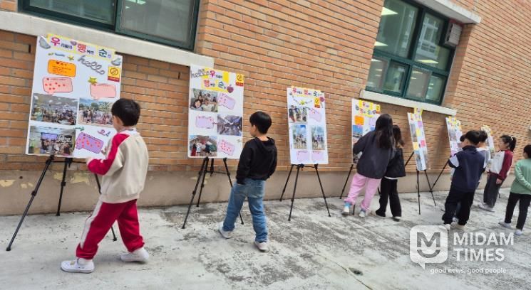 덕신초 학생들이 교내에 전시된 '우리들의 행복한 순간' 사진을 관람하고 있다.