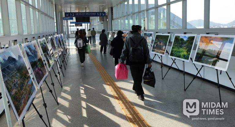 영천역 승강장 입출구 통로에 전시된 제17회 영천관광 전국사진공모전 입상작품을 철도 이용객들이 관람하고 있다.
